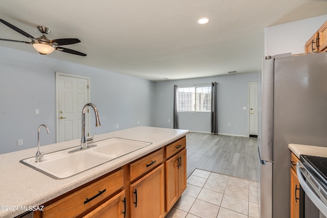 kitchen featuring appliances with stainless steel finishes, light hardwood / wood-style flooring, sink, and ceiling fan