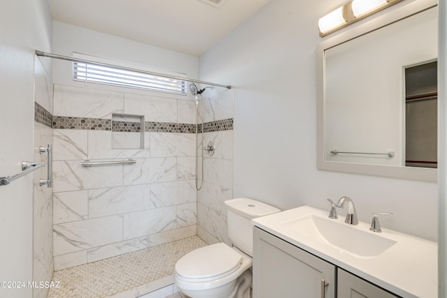 bathroom with vanity, tiled shower, toilet, and tile patterned floors