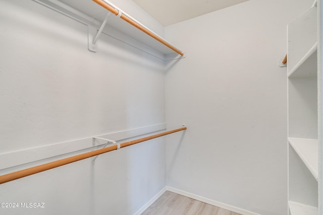 walk in closet with light hardwood / wood-style floors