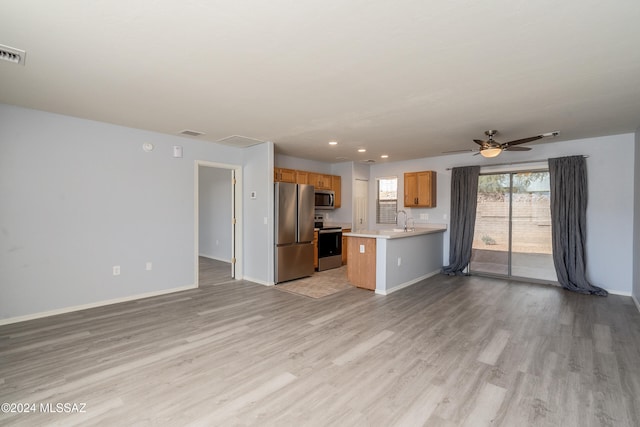 kitchen with kitchen peninsula, ceiling fan, appliances with stainless steel finishes, light wood-type flooring, and sink