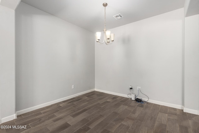 empty room with dark hardwood / wood-style floors and a chandelier