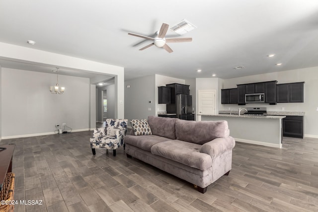 living room with dark hardwood / wood-style floors and ceiling fan with notable chandelier