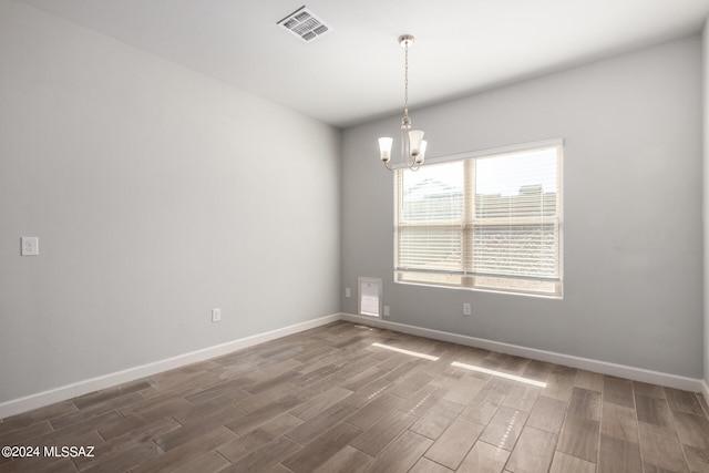 unfurnished room with a notable chandelier and dark hardwood / wood-style flooring