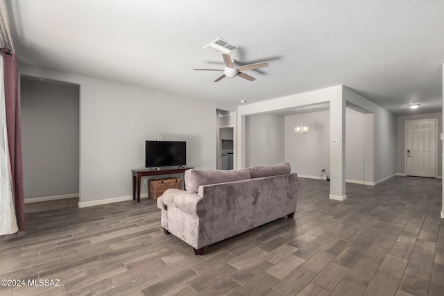 living room with dark wood-type flooring and ceiling fan with notable chandelier