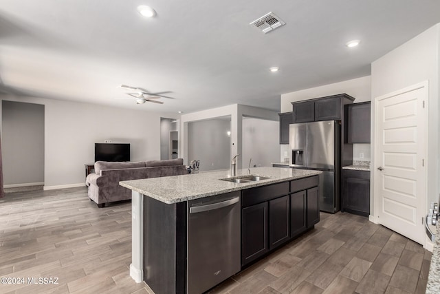 kitchen featuring a center island with sink, ceiling fan, appliances with stainless steel finishes, light wood-type flooring, and sink