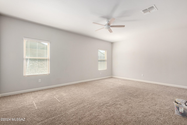 spare room with a wealth of natural light, carpet flooring, and ceiling fan