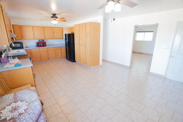 kitchen featuring range, light tile patterned floors, black refrigerator, light brown cabinets, and ceiling fan