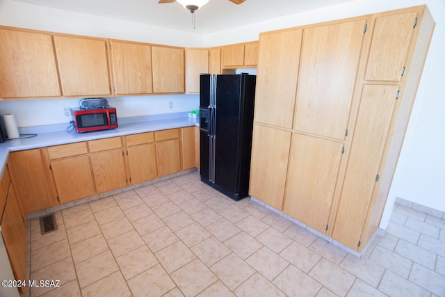 kitchen featuring light tile patterned floors, ceiling fan, and black fridge