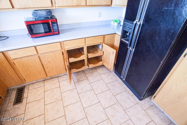 kitchen featuring light tile patterned flooring, light brown cabinets, and black fridge with ice dispenser