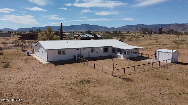 back of house with a storage shed and a mountain view