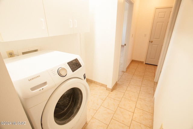 clothes washing area featuring washer / clothes dryer, light tile patterned flooring, and cabinets