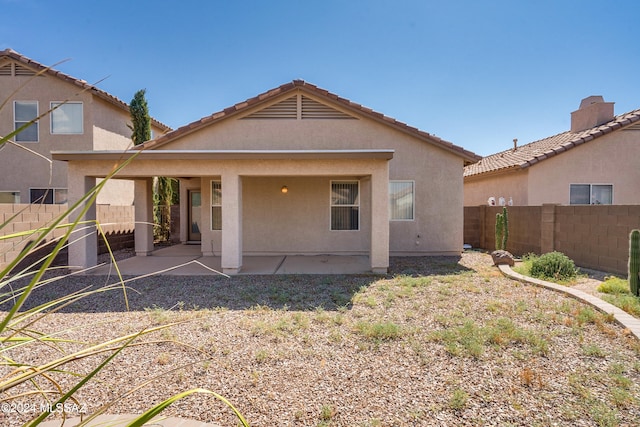 rear view of property featuring stucco siding, a patio, and a fenced backyard