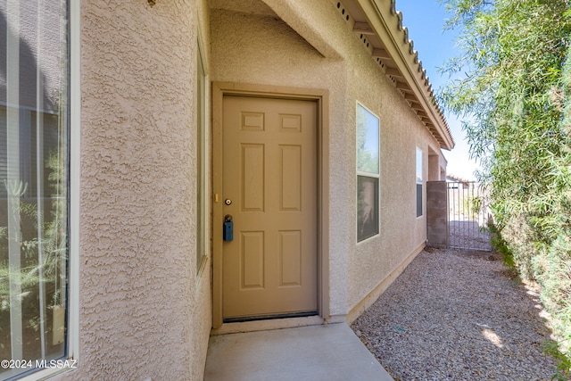 entrance to property featuring fence and stucco siding