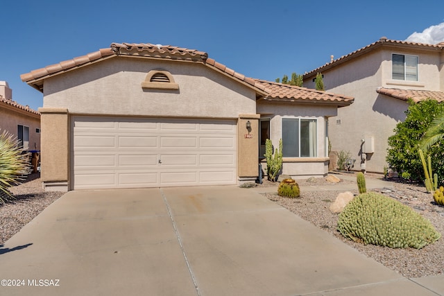 mediterranean / spanish house featuring a tiled roof, stucco siding, driveway, and a garage