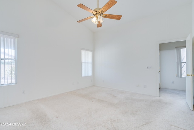 empty room featuring light colored carpet, high vaulted ceiling, and ceiling fan