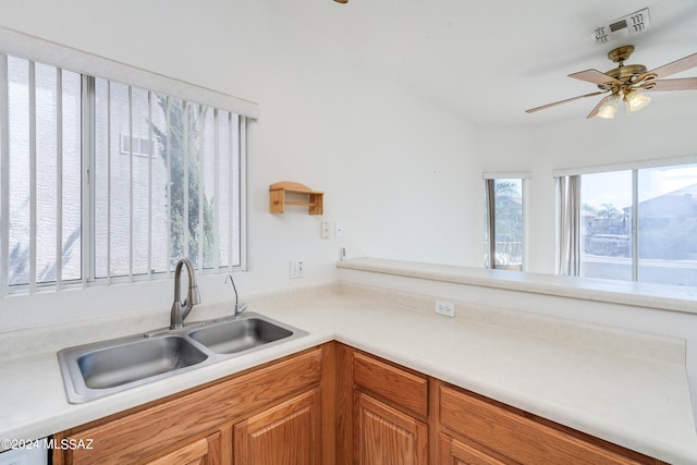 kitchen with a sink, visible vents, brown cabinets, and light countertops