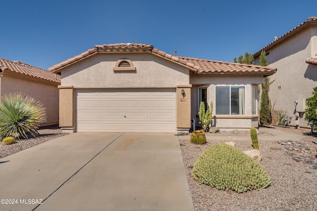 mediterranean / spanish home featuring stucco siding, a garage, concrete driveway, and a tiled roof