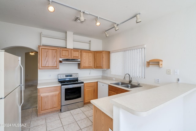 kitchen featuring white appliances, a peninsula, arched walkways, a sink, and under cabinet range hood