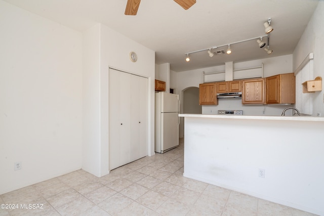 kitchen with kitchen peninsula, ceiling fan, stainless steel stove, sink, and white refrigerator