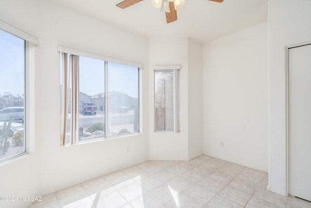 tiled spare room featuring ceiling fan