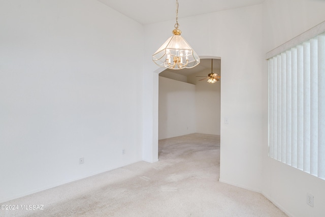 carpeted empty room with ceiling fan with notable chandelier