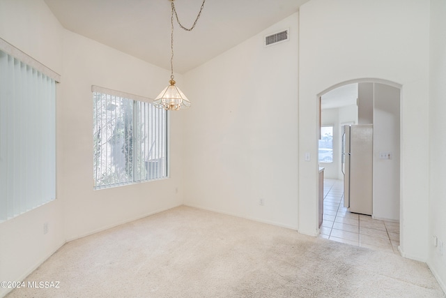 carpeted empty room with an inviting chandelier