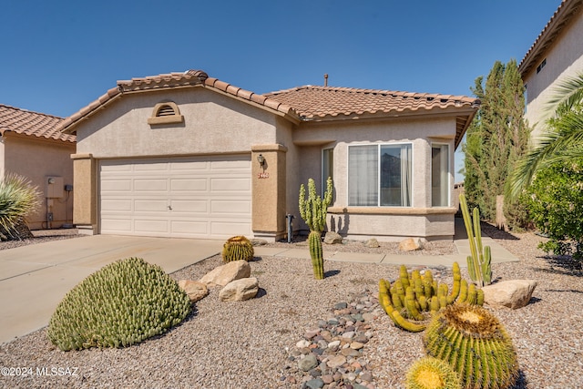 mediterranean / spanish-style house with a tiled roof, a garage, driveway, and stucco siding