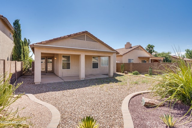 rear view of property featuring a fenced backyard, a chimney, stucco siding, a tiled roof, and a patio area