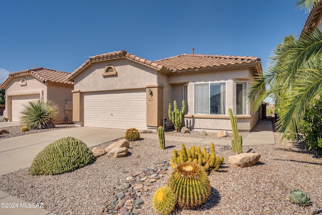 mediterranean / spanish-style house with stucco siding, driveway, a tile roof, and a garage