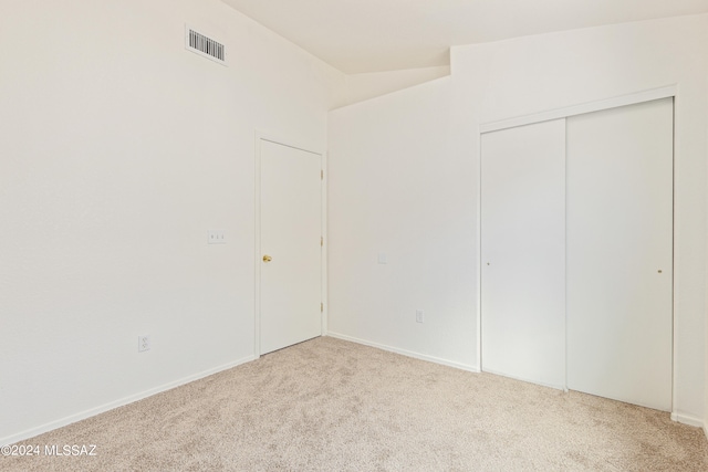 unfurnished bedroom featuring light carpet and a closet