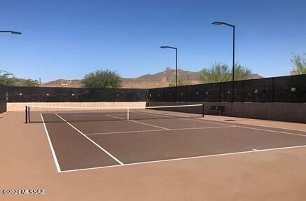 view of tennis court featuring community basketball court and fence