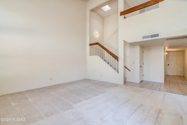 interior space with a high ceiling, light carpet, and a skylight