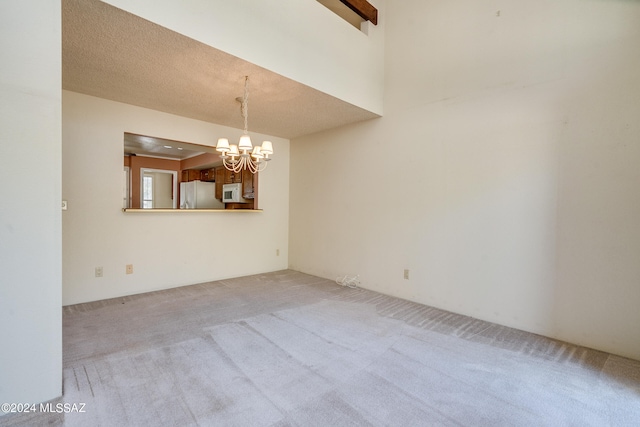 carpeted empty room featuring an inviting chandelier and a textured ceiling