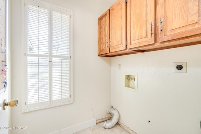 laundry area featuring cabinets, hookup for an electric dryer, light tile patterned floors, and a wealth of natural light