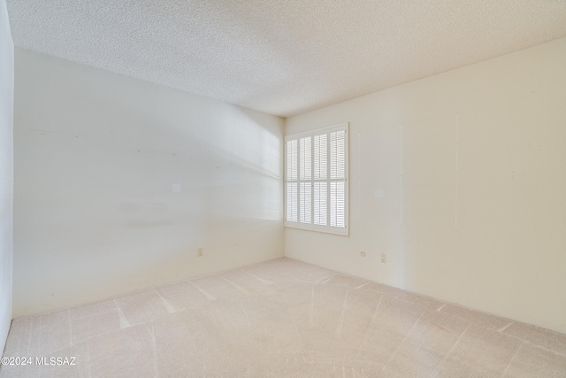 spare room featuring light carpet and a textured ceiling