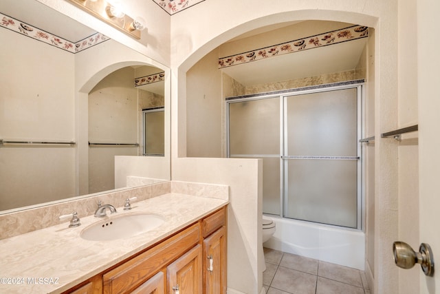 full bathroom with vanity, shower / bath combination with glass door, toilet, and tile patterned flooring