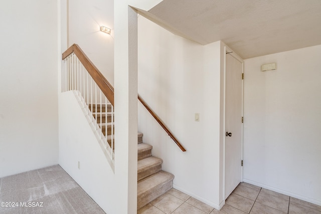 stairway with tile patterned floors and a textured ceiling