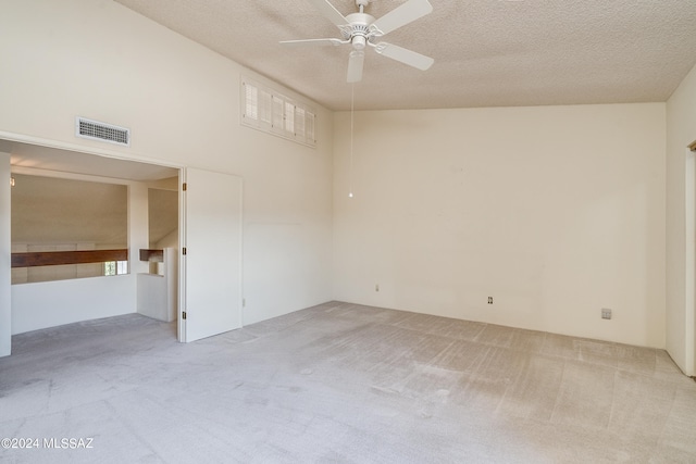 spare room featuring light carpet, a textured ceiling, and ceiling fan