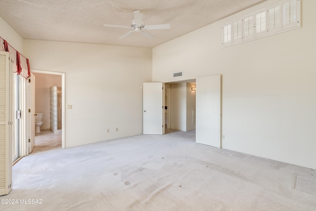 unfurnished bedroom featuring a textured ceiling, light colored carpet, high vaulted ceiling, and ceiling fan
