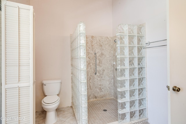 bathroom featuring toilet, tile patterned flooring, and tiled shower
