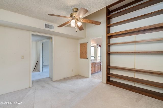 interior space with ceiling fan, a textured ceiling, and light colored carpet