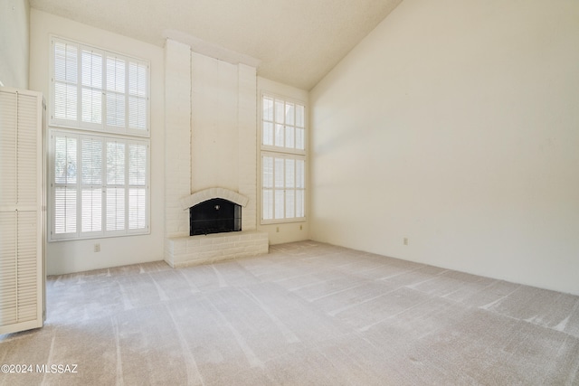 unfurnished living room with light carpet, a brick fireplace, and high vaulted ceiling