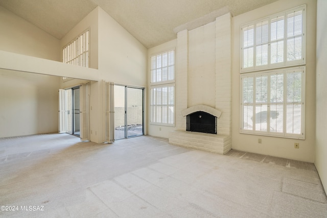 unfurnished living room with a textured ceiling, a fireplace, light colored carpet, and plenty of natural light
