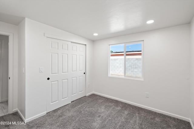 unfurnished bedroom with dark carpet and a closet