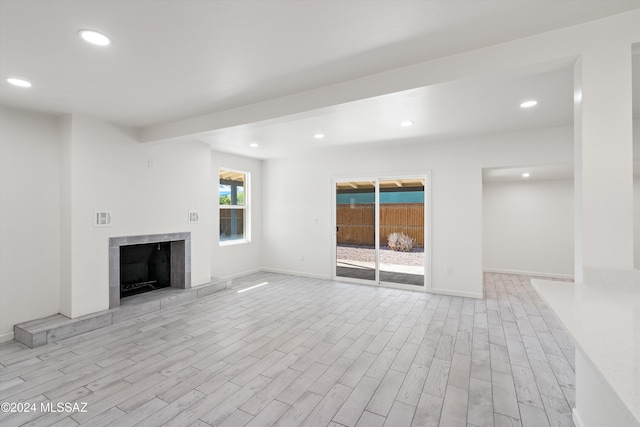 unfurnished living room featuring light wood-type flooring and a tiled fireplace