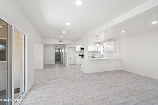 kitchen with white cabinetry, sink, light hardwood / wood-style flooring, kitchen peninsula, and pendant lighting