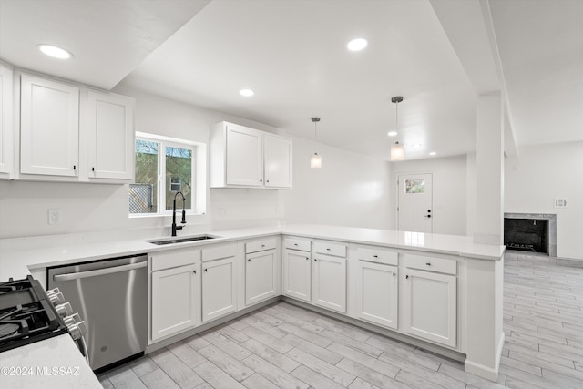 kitchen featuring sink, stainless steel appliances, kitchen peninsula, pendant lighting, and white cabinets