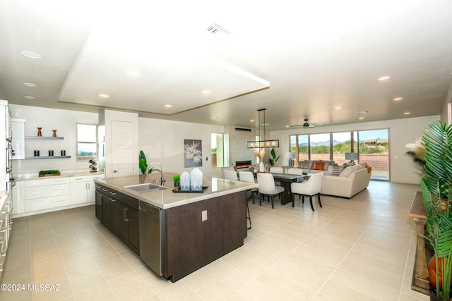 kitchen with sink, white cabinetry, light tile patterned flooring, and an island with sink