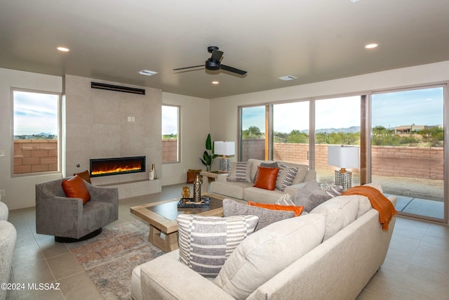 tiled living room featuring a large fireplace and ceiling fan