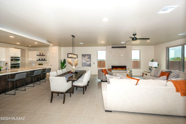 living room with light tile patterned flooring, a large fireplace, and ceiling fan